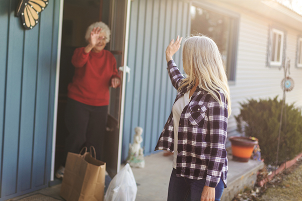 caregiver delivering groceries to older adult