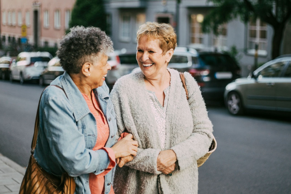 Two older women walking, smiling at each other