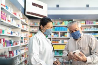 patient wearing mask showing medication to pharamacist wearing mask