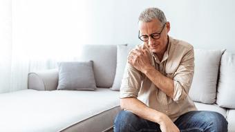 An  older man holding his shoulder in pain