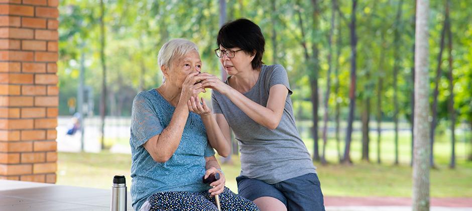 caregiver helping older adult drink out of cup